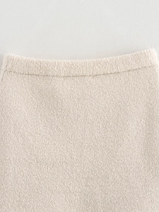 Nahaufnahme von cremefarbenem Strickstoff mit Bouclé-Textur und Bunddetails