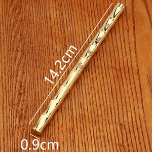 Detailed view of golden bamboo-shaped brass pen on wood background with size markings