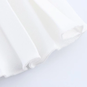 Close-up of pleated white fabric showing delicate knitted texture and hemline details