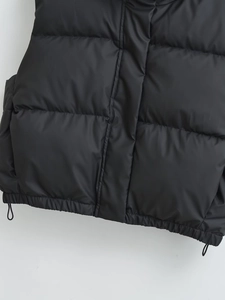 Detail of black puffer vest featuring quilted stitching and adjustable drawstring hemline