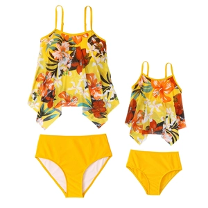 Detail of matching mother and daughter swimsuits with tropical floral print and yellow bottoms