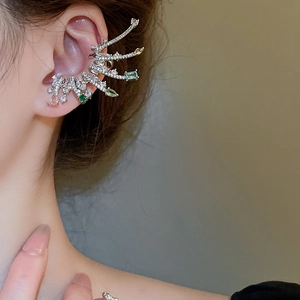 Gros plan d'un ear cuff en argent élégant avec ailes en zircon vert et gemmes