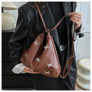 Dettaglio di una borsa in pelle marrone con farfalle argentate indossata da una modella