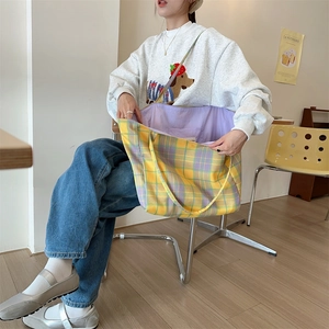 Detail of checkered canvas tote bag showing purple interior lining in a cafe setting
