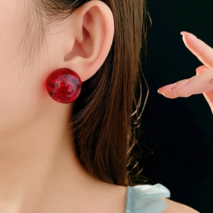 Close-up of translucent red resin stud earring with gold leaf texture on female model