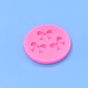 Pink silicone mold featuring three detailed bow shapes for fondant and cake decoration