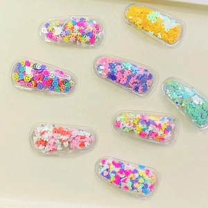 Detail of colorful sequins and heart shapes inside transparent BB hair clips for girls