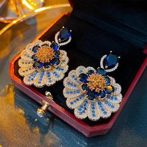 Detail of luxury flower earrings with blue and orange gemstones in a red jewelry box