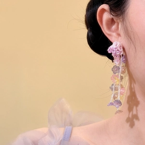 Detail view of colorful floral beaded tassel earrings worn on ear for vacation vibes