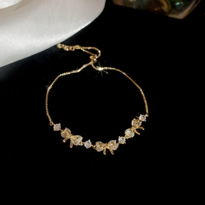 Close-up of gold plated bow bracelet with opal and adjustable slider on black velvet