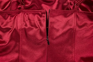 Detailed close-up of a black invisible zipper on a dark red satin evening dress back