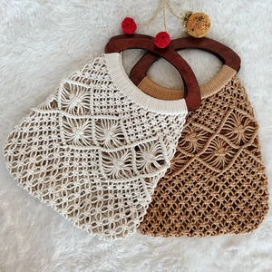 Bohemian crochet tote bags with wooden handles and decorative pom-poms on white fur