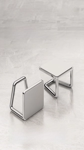 Macro shot of two silver stainless steel adhesive hooks on a grey marble background