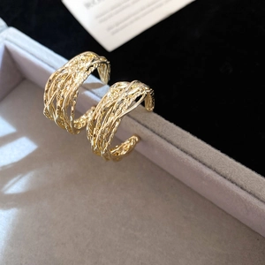 Close-up of golden vintage twisted hoop earrings with textured metal weave design