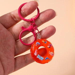 Detail of red donut lifebuoy keychain with pink metal clip held by hand on beige background