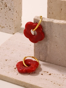 Detailed shot of red flower enamel earrings on a natural marble stone surface