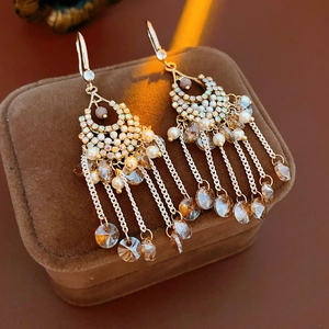 Close-up of gold tassel earrings with zircon, crystals and pearls on a velvet box