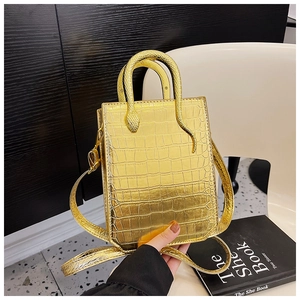 Close-up of golden embossed crocodile texture tote bag with creative snake-shaped handle