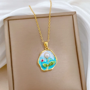 Macro detail of gold necklace featuring blue enamel pendant with pearl and tiny gemstone