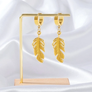 Golden feather-shaped titanium steel leaf drop earrings hanging on a minimal display stand