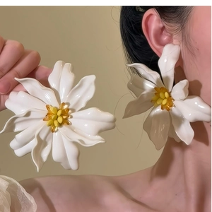 Macro detail of large white acrylic floral earrings with resin petals and yellow stamens