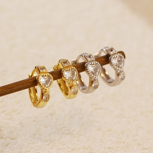 Macro shot of gold and silver heart-shaped zircon earrings hanging on a display