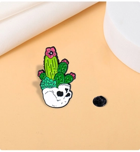 Macro shot of punk cactus skull enamel pin with a black rubber clutch on minimalist background
