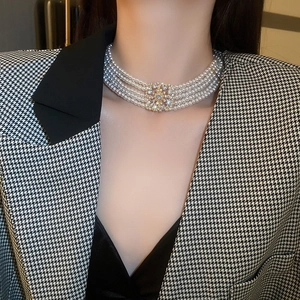 Close-up of a multi-layer pearl choker with a square crystal rhinestone buckle on a model