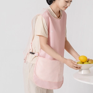 Pink breathable mesh apron with front pocket and side buckles shown on model in kitchen