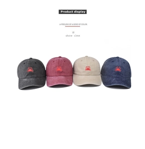 Close-up of four washed cotton baseball caps with red crab embroidery details