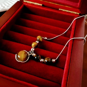 Détail d'un collier avec pendentif œil de tigre dans un écrin en velours rouge