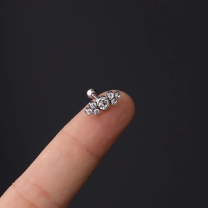 Macro shot of 16g curved stainless steel ear cartilage stud with white zircon cluster