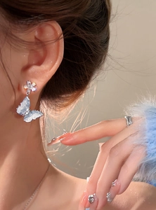Detailed view of elegant blue ice-transparent butterfly earrings with crystal flower stud