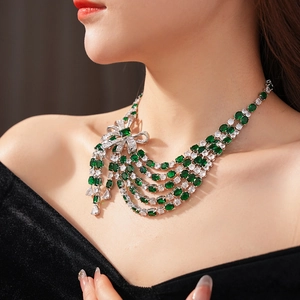 Gros plan du collier nœud argenté avec gemmes vertes et glands multicouches sur un mannequin
