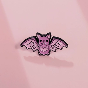 Cute purple bat enamel pin with YOU SUCK wings on a minimalist pink background