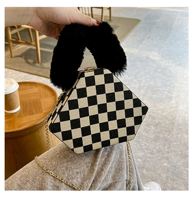 Detail of checkered hexagonal handbag with plush black handle and gold chain strap