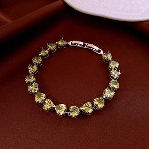 Macro shot of silver-plated bracelet featuring green heart-shaped zircon stones