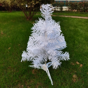 Close-up of a dense white artificial Christmas tree with snow-like texture on a tripod base