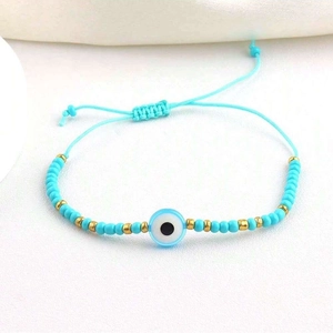 Detail of adjustable blue devil eye beaded bracelet with gold accents on white base