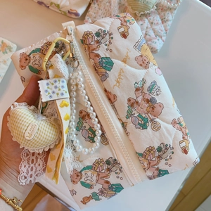 Close-up of quilted cotton makeup bag with bear prints and decorative pearl chain