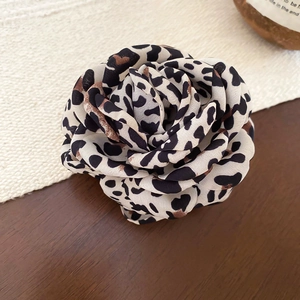 Détail d'une pince à cheveux rose en tissu à motif léopard sur une table en bois rustique