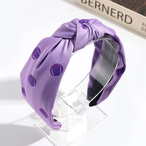 Detailed view of a purple knotted headband with tennis ball patterns on a display stand