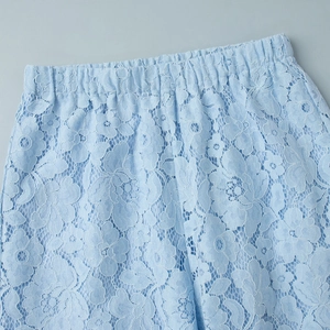 Close-up of light blue floral lace fabric with elastic waist detailing on trousers