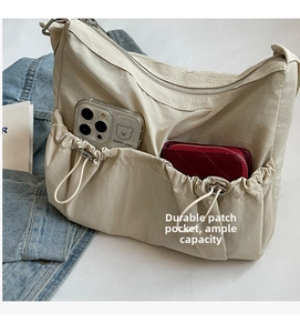 Detail of cream nylon crossbody bag with multi-pocket storage and drawstring front