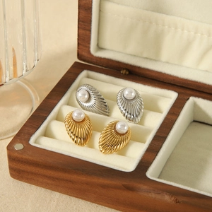 Elegant shell-shaped earrings in gold and silver finish with white pearls in a jewelry box