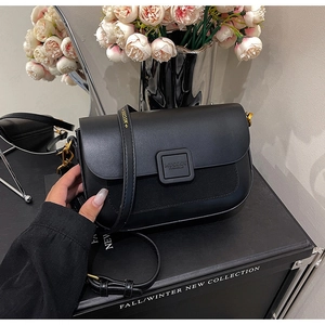 Close-up of black crossbody bag with premium leather texture and gold buckle detail