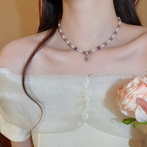 Detailed close-up of a pearl and purple bead necklace with a square zircon pendant on neck