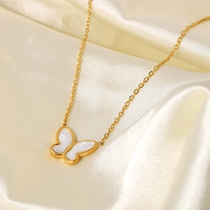 Detail of 14K gold stainless steel butterfly necklace on a luxury white silk background