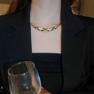 Close-up of elegant gold plated curved necklace with crystals worn on a female model