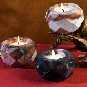 Three faceted marble texture scented candles with geometric shapes on wood